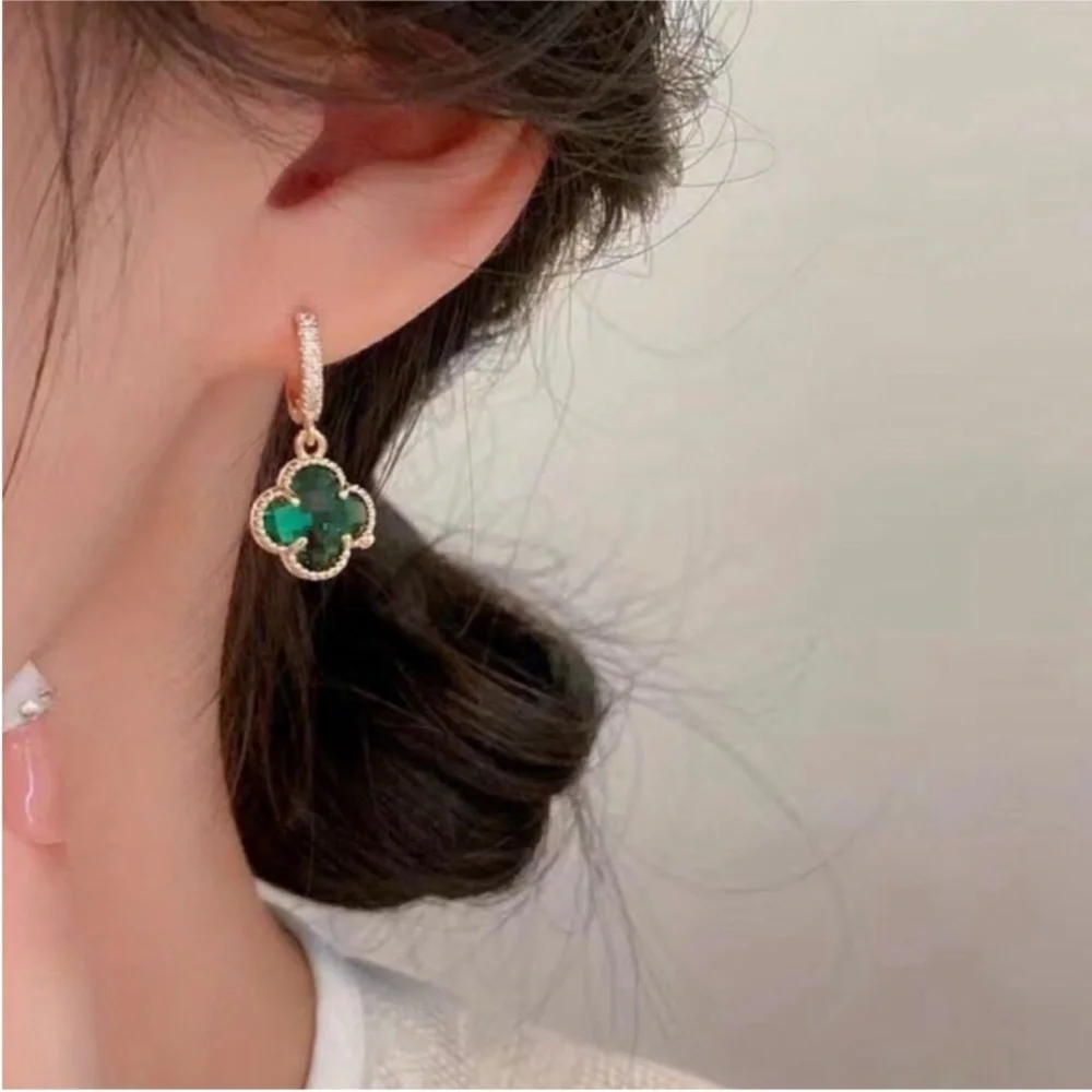 clover-shaped dangle earrings featuring green stones and gold plating with paved